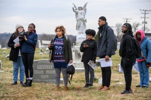 Six students with cameras standing in a gray cemetary